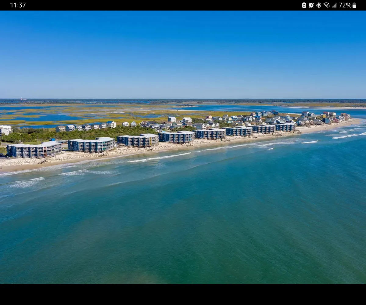 A sweeping exterior view of beachfront properties with the ocean waves rolling in and a picturesque coastal landscape. The scene invites guests to imagine sunbathing, swimming, or leisurely walks along the shoreline.
