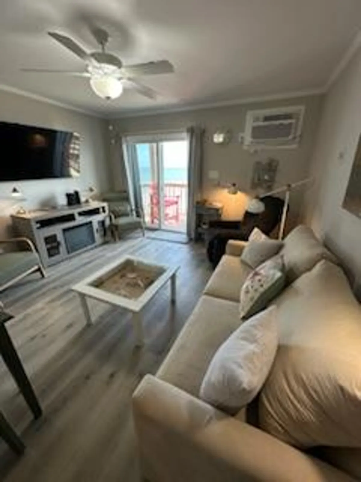This image depicts a cozy living room with a comfortable sofa, a coffee table, and a smart TV. The main highlight is the large balcony doors that open to sweeping views of the Atlantic Ocean, with sunlight pouring into the space. The scene seamlessly blends indoor comfort with outdoor beauty, inviting relaxation and socializing.
